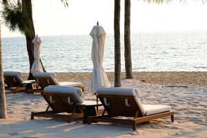 Two chaise lounges and straw umbrella on tropical beach. Coast of island Koh Rong Samloem, Cambodia. free empty copy space for text photo