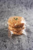 Close-Up of Three Coconut Cookies in Plastic Wrapping on Grey Background. Sagon is a typical Indonesian cake made from glutinous rice flour and grated coconut photo