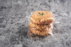 Close-Up of Three Coconut Cookies in Plastic Wrapping on Grey Background. Sagon is a typical Indonesian cake made from glutinous rice flour and grated coconut photo