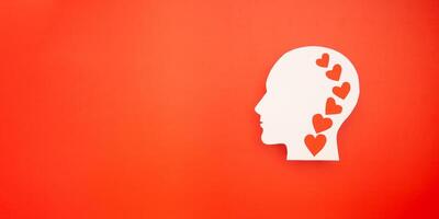 Top view of a white head with a red heart made from paper on a red background photo