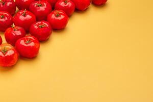 Top view of ripe red acerola cherries on an orange background photo