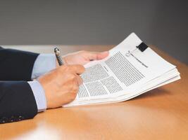 Close-up of a businessman signing on documents while sitting working in the office photo