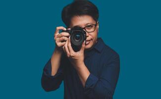 A Photographer holding a digital camera while standing on a blue background photo