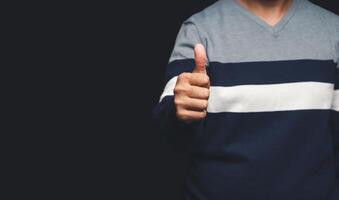 A close-up of the hand shows thumbs up while standing on gray background with copy space for text photo