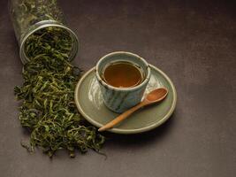 Dry cannabis leaf tea outside a box and marijuana tea cup on vintage background photo