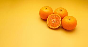 Pile of fresh oranges on a yellow background with copy space for text photo