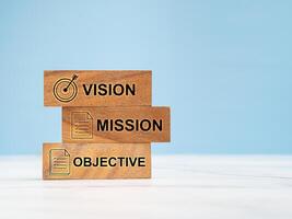 Vision, Mission, and objective on the wooden cubes on a marble table against a blue background photo