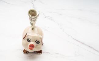 Lovely piggy bank with US dollar banknote on a marble background photo