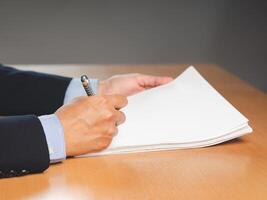 Close-up of a businessman signing on documents while sitting working in the office photo
