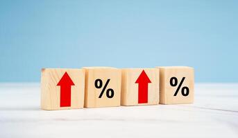 Finance and interest rate concept. Wooden cubes with arrows up and percentage symbol over a blue background photo