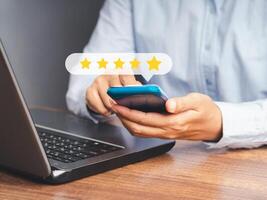 A customer using a smartphone gives the five-star icon a rating of very impressed for service while sitting in the office photo