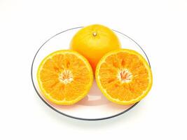 Top view of oranges cut half and whole on a white dish over a white background photo