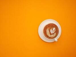 Top view of a fresh coffee cup over an orange background photo