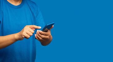 Close-up of hands man in a blue casual using a mobile phone while standing on a blue background photo