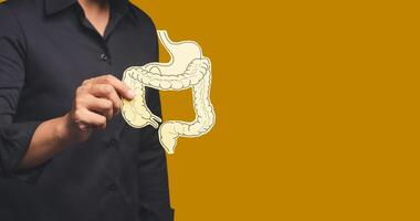 Close-up of hand holding a colon symbol while standing on an orange background photo