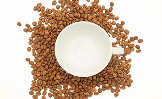 Top view of fresh aromatic roasted coffee beans and an empty white coffee cup on a white background photo
