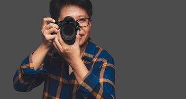 A Photographer holding a digital camera while standing on a gray background photo