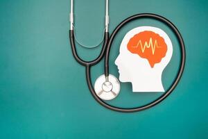 A brain shape made from paper and a stethoscope on a green background photo