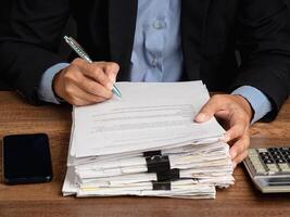 Hand of a businessman in a suit signing on lease contract or agreement while sitting in the office photo