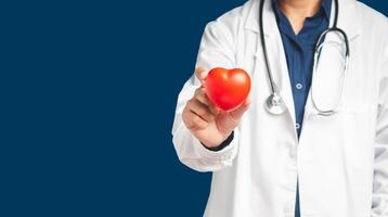 Doctor in uniform holding holding a red heart shape while standing on a blue background photo