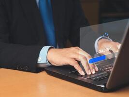 Businessman uses a laptop for loading and processing data on a virtual screen photo