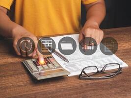 Tax day concept. A young man in an orange casual using a calculator to calculate taxes while sitting in the office photo