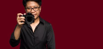 Photographer with a camera. Tomboy's holding the digital camera while standing on a red background photo
