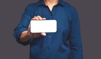 Close-up of hand holding a horizontal mobile phone with a blank white screen while standing on a gray background photo