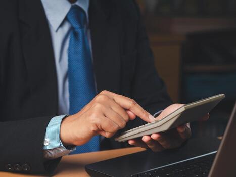 Close-up of a businessman in a suit sitting working in the office using a calculator to calculate the numbers photo