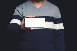 Close-up of hand holding a horizontal mobile phone with a blank white screen while standing on a black background photo