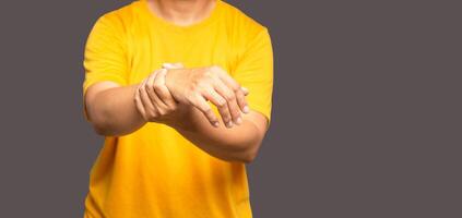 Close-up of hands young man suffering from wrist pain while standing on a gray background photo