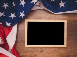 Top view of the American flag and empty blackboard over a wooden table photo