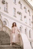 woman in elegant coat and hat against an intricate architectural backdrop, harmoniously blending modern fashion with historical allure. The soft daylight adds to its timeless appeal. photo