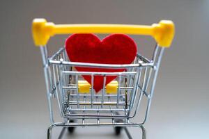 Shopping basket on a gray background with a bright red heart. Close-up. photo