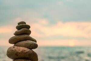 Stones Stack Beach Sunset - Balanced stones tower on a beach with a cloudy sunset in the background. photo