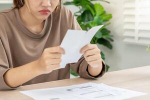 Stressed and headache asian woman with large bills or invoices no money to pay to expenses and credit card debt. shortage, Financial problems, mortgage, loan, bankruptcy, bankrupt, poor, empty wallet photo