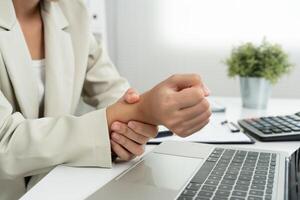 business young woman working in office with a carpal tunnel syndrome or wrist joint inflammation, hand muscle inflammation from office syndrome , hand muscle pain from working photo