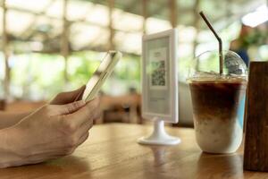 Woman use smartphone to scan QR code to pay in cafe restaurant with a digital payment without cash. Choose menu and order accumulate discount. E wallet, technology, pay online, credit card, bank app. photo