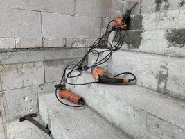 Electric drill on a concrete stairs in a construction site background photo