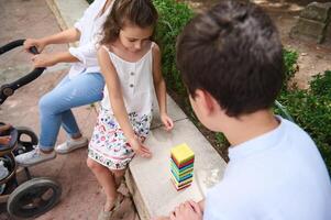 Children playing with colorful blocks in a park setting with family photo