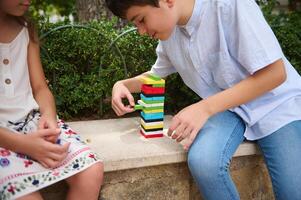 Children playing a colorful block stacking game outdoors on a sunny day photo