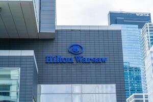 The building and logo of the Polish hotel Hilton Warsaw. Office building skyscraper in the city center. Warsaw, Poland - July 26, 2023. photo