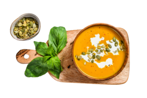 Pumpkin soup with cream, seeds and fresh basil in rustic wooden bowl. gray background. Top view png