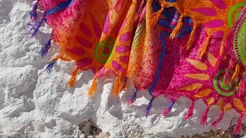 Folds of trembling silk textile fabric with thread tassels shaking in wind. Red waving cloth on white stone background. Summer beach scarf with fringe video