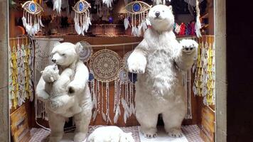 Three plush polar bears move in shop display among dreamcatchers and decorative items, creating a playful winter atmosphere that attracts shoppers attention. video