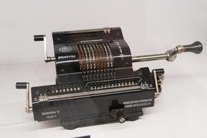 The adding BRUNSVIGA machine is the first prototype of a calculator on white background. Antique mechanical device. Poland, Warsaw - July 28, 2023 photo
