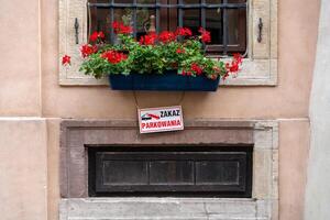 Pointer on the house under the window about the prohibition of parking. Flowers in a hill on the windowsill. Layout template sign photo