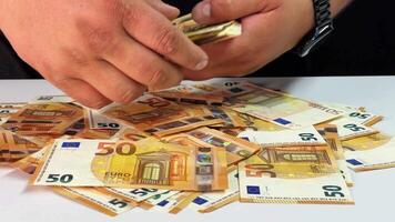 A person is carefully sorting through a stack of Euro bills, ensuring each note is neatly arranged. The focus is on the handling of currency in an everyday environment video