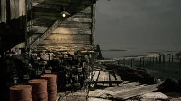 Old wooden structure near water with barrels and dim lighting at twilight video