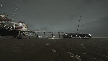 Abandoned boat at low tide near a weathered pier in a coastal area video